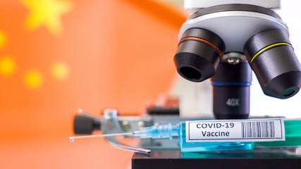 Fototapeta na wymiar The China flag on the back of the microscope with the coronavirus sryinge