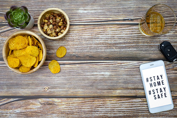 Smart phone screen with text hashtag #STAY HOME and #STAY SAFE. with snacks and beverages. stay home stop virus concept.