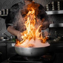 chef in action with a frying pan on high heat