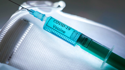 The syringe for the coronavirus vaccine COVID-19 on the white mask