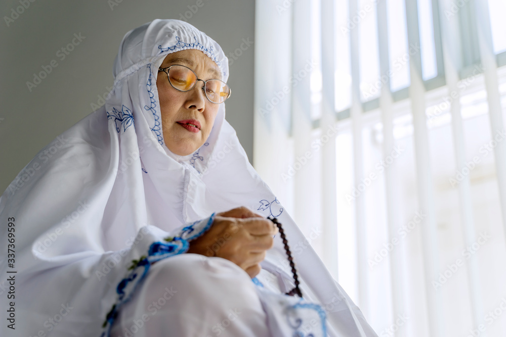 Wall mural Old muslim woman holding rosary beads