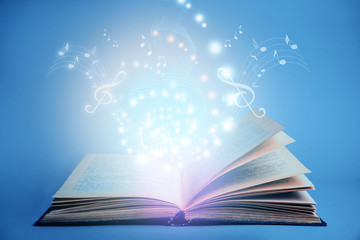 Symphony shining with musical notes from open book on blue background