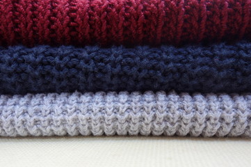 Pile of knitted cotton pullovers of different colors