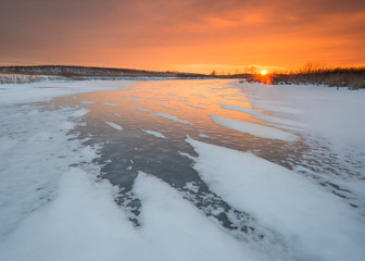 Golden sunset light reflects off of a frozen marsh at a Midwest wetland conservation area.