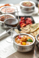 Indian cuisine dish with a glass of red wine on a restaurant table