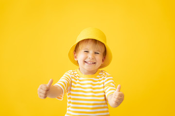 Portrait of happy child against yellow background. Summer vacation concept