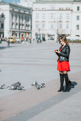 Attractive girl feeds pigeons on the market. There is beautiful weather