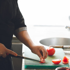 chef cuts tomatoes on the kitchen board