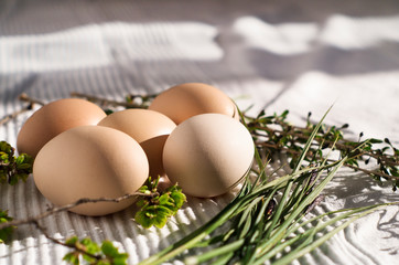 Homemade eggs on a white cloth. Decorated with green branches and grass.