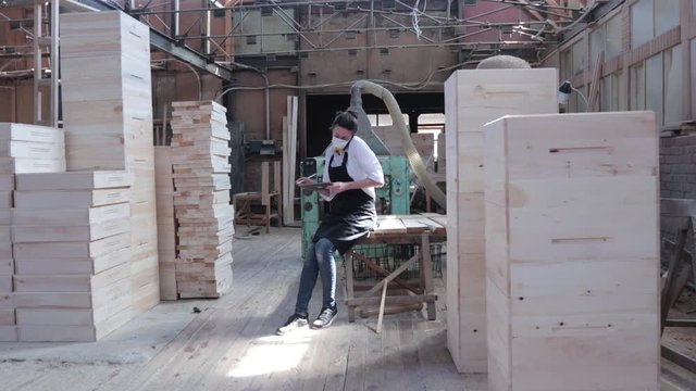 Confident Woman Working As Carpenter In Her Own Woodshop. She Using A Tablet Pc And Writes Notes While Being  In Her Workspace. Small Business Concept.