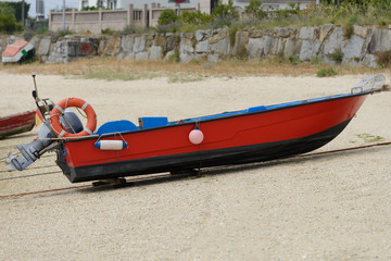 Fototapeta premium red wooden fishing motor boat dries ashore.