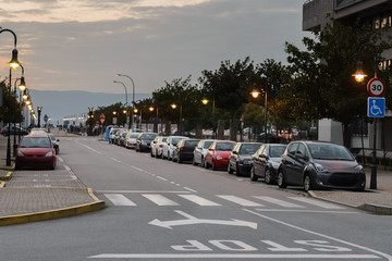 cars parked in a row on a city street at sunset