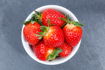 Strawberries berries from above bowl slate