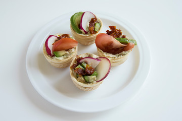 White plate with ready-made tartlets on a white background.