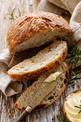 Homemade sourdough bread with rosemary cut into slices with the addition of fresh butter on a...