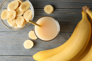 Bananas and juice on wooden background, top view