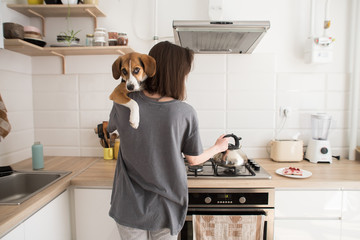 young woman cooks in the kitchen with a dog