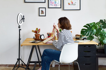 Female artist filming design workshop at home for online education. Working from home making...