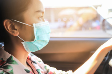 girl wearing surgical mask driving car in town 