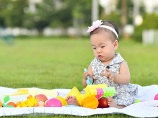 Cute Asian baby girl playing with toys in playground