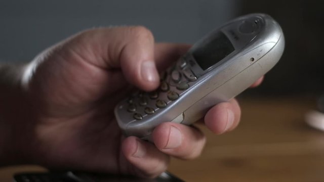 close-up of a man's hand tapping a phone number on the keyboard of a scratched, outdated cell phone. Macro shooting of buttons on the keyboard of outdated mobile phones. Modern wireless technology.