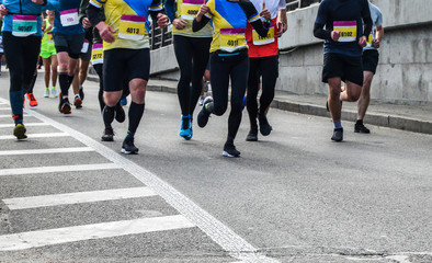 Detail of a group of runners during a city marathon. Legs and sneakers. Muscles under stress. Sport concept