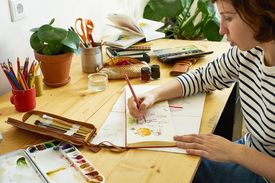 Close-up image of artist drawing in a sketchbook. Female designer working from home. Creative cozy workplace
