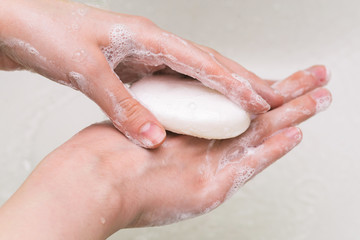 Fototapeta premium Hand washing with soap. The girl uses soap and washes her hands under a water tap. Hygiene concept. Coronavirus virus prophylaxis.