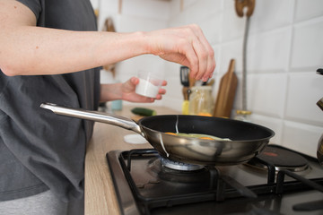 young girl prepares eggs in light kitchen, scandinavian style