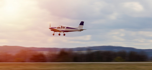 Ultralight plane take off from runway on airports with cloud sky and sun. Panning photo