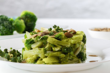 Boiled broccoli with pumpkin seeds on a white plate on the table