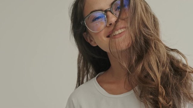 Happy pretty brunette woman in eyeglasses playing with her hair at home