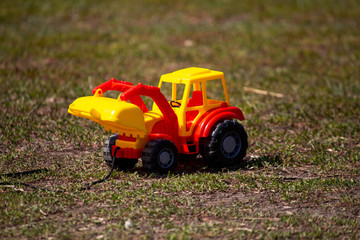 Toy yellow-red tractor on the ground, children's things
