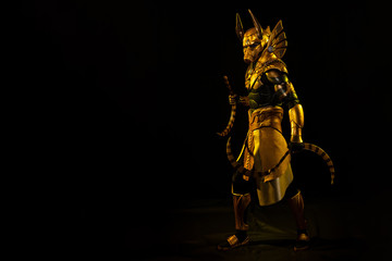 a male actor in a suit of an Egyptian mythology character, the golden deity Jackal Anubis, twists...