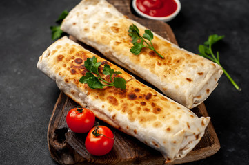 Burrito wraps with chicken and vegetables , against a background of concrete, 
 Mexican shawarma