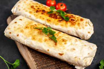 Burrito wraps with chicken and vegetables , against a background of concrete, 
 Mexican shawarma