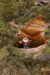 The crack in a limestone cliff with a dwarf toy in it. A small cave in a rock with a small gnome...