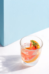 Refreshing cold summer drink in a glass with slice of grapefruit and ice cubes on a white table...