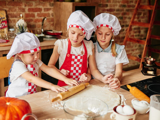 Three little chefs enjoying in the kitchen making cakes. Girls at the kitchen. Family housekeeping.