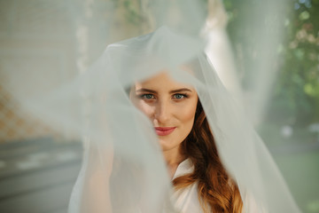 Beauty portrait of a beautiful blonde bride in veil with a bouquet of flowers in his hands on a gray background.