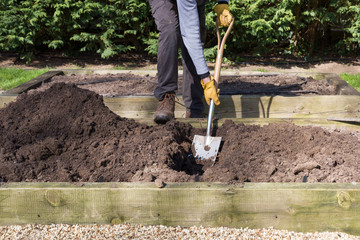 Man digging a hole with a shovel in a garden, UK © Paul Maguire
