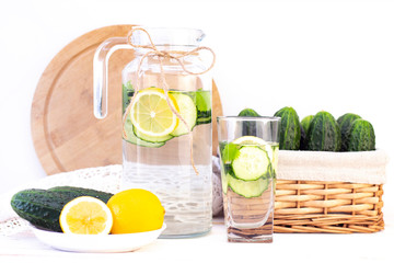 Health care, fitness, healthy eating concept. Fresh cool lemon cucumber drink with water, cocktail, detox drink, lemonade in a glass jug and a glass. wicker basket with cucumbers