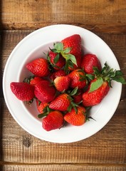 Juicy strawberries in a white plate on the table