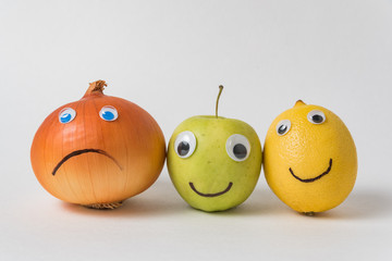 Napiform onion, Apple and lemon with funny faces on white background. Concept of multinational...