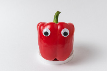 Raw red peppers with Googly eyes on white background. Pepper with funny face