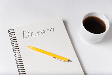 Notepad with the words Dream on white background. Pen coffee on notebook.