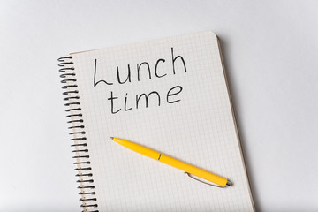 Top view of notebook with LUNCH TIME inscription. Copybook and pen white background