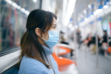 A young Asian woman wearing a surgical mask in the subway.