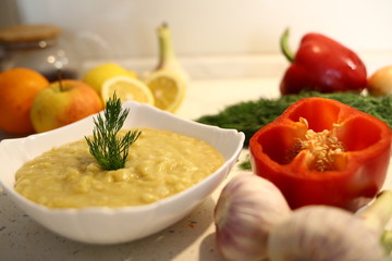 appetizing lentil porridge 
in a white dish, healthy eating background of various fruits and vegetables on a light kitchen countertop. Vegetarians. Lean food