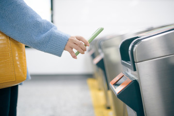 Young woman using smart phone to pay at metro station.